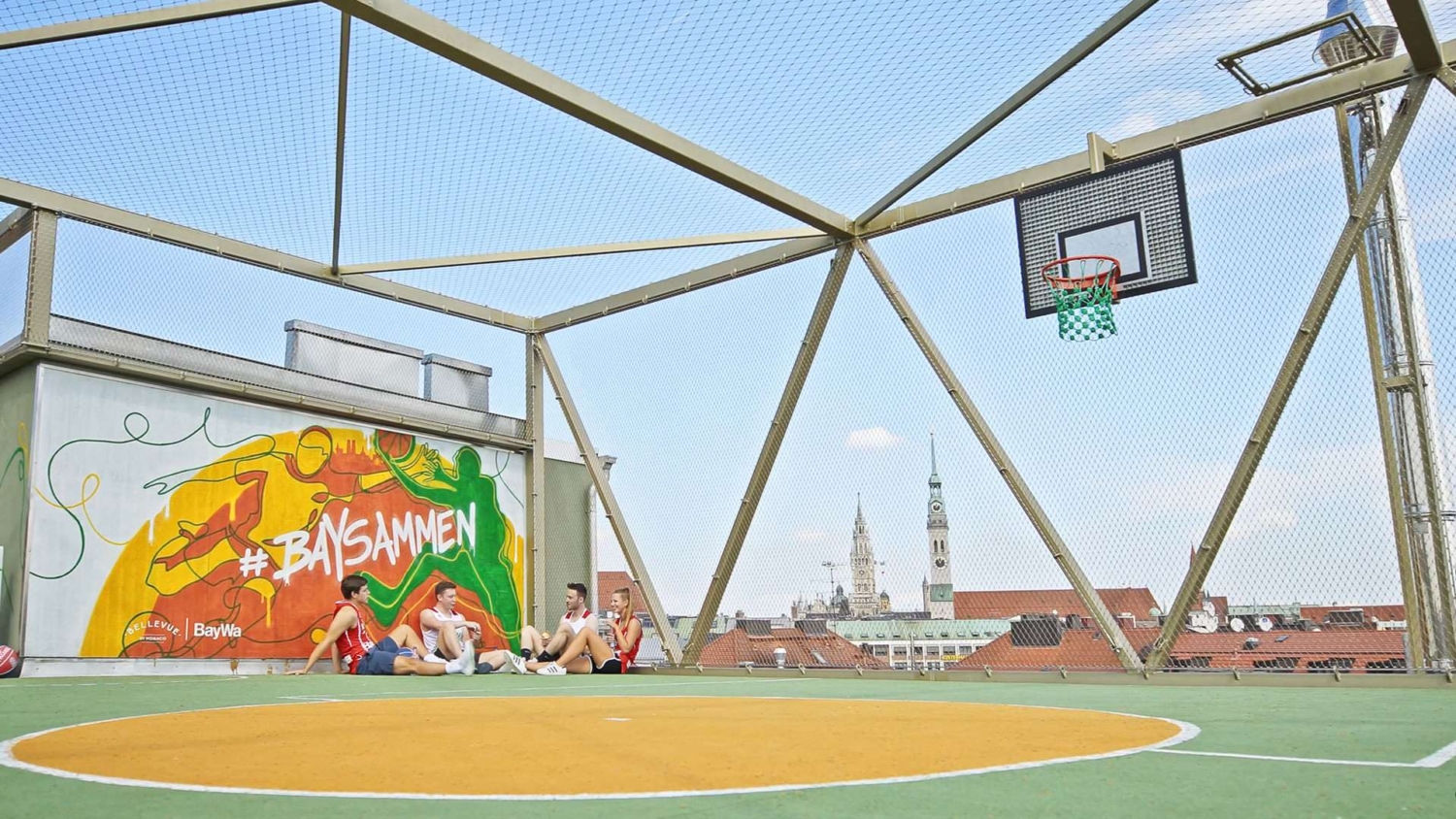 Der einzigartige Bolz- und Basketballplatz auf dem Dach des Bellevue di Monaco, realisiert mit Unterstützung der BayWa AG, ergänzt durch ein beeindruckendes Graffiti von Künstler Lando.