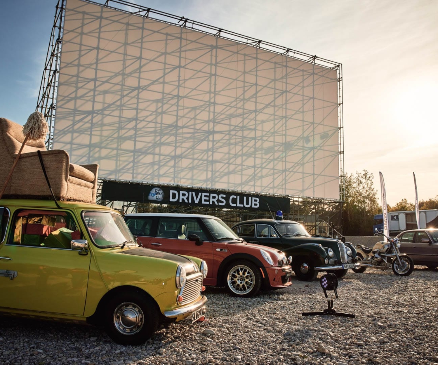 Mini-Flotte mit Mr. Bean Auto vor der Autokinoleinwand des Drivers Club
