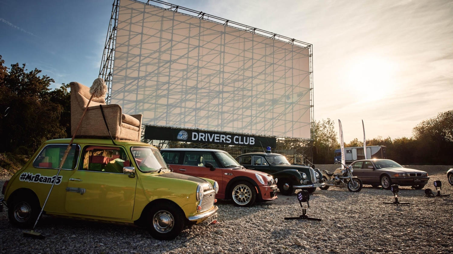 Mini-Flotte mit Mr. Bean Auto vor der Autokinoleinwand des Drivers Club