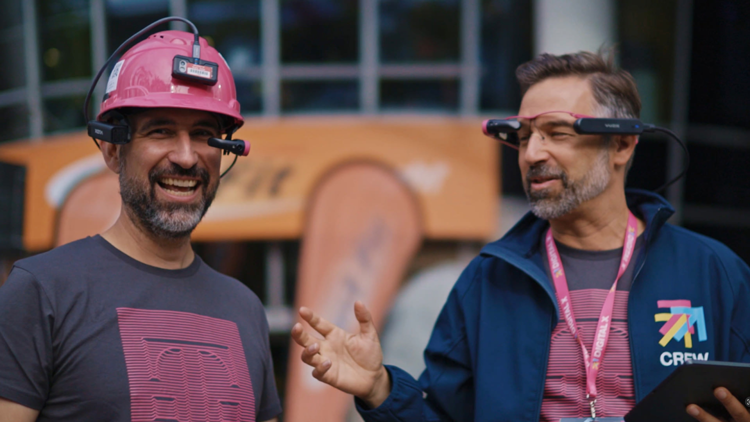 Zwei Männer mit Augmented-Reality-Brillen und Telekom-Shirts im Gespräch auf der DIGITAL X Messe in Köln