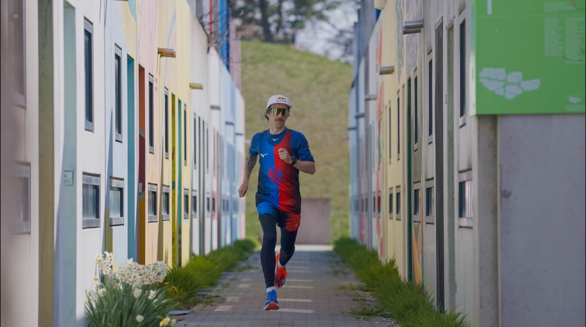 Ultraläufer Florian Neuschwander läuft zwischen bunt bemalten Häusern im Olympischen Dorf München