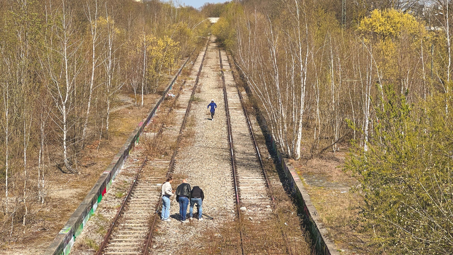 Drohnenaufnahme des Drehs mit Florian Neuschwander im Olympiapark München – Flo läuft auf Gleisen, das Filmteam steht im Vordergrund