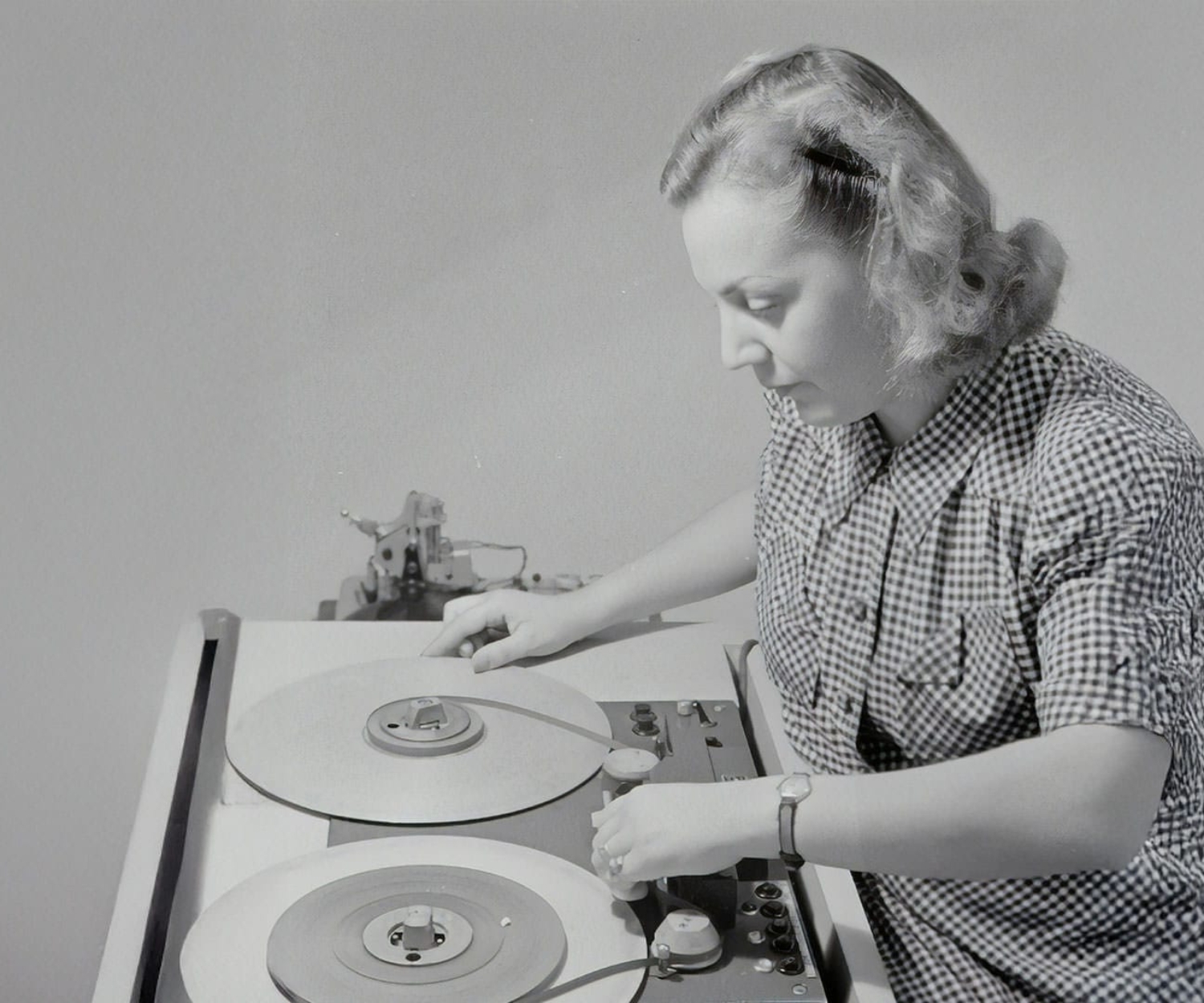 Eine Cutterin bei der analogen Filmmontage an einem historischen Schneidetisch – Symbol für die Anfänge der Postproduktion