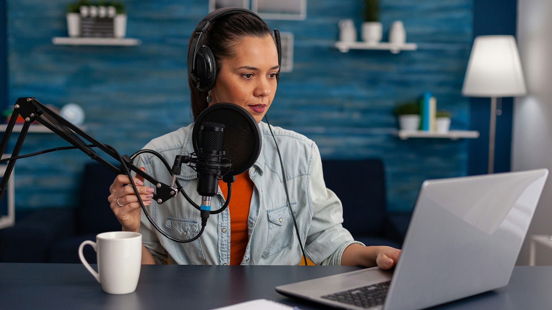 Frau mit Kopfhörern und Mikrofon spricht ein Voice-over für eine B2B-Videoproduktion ein