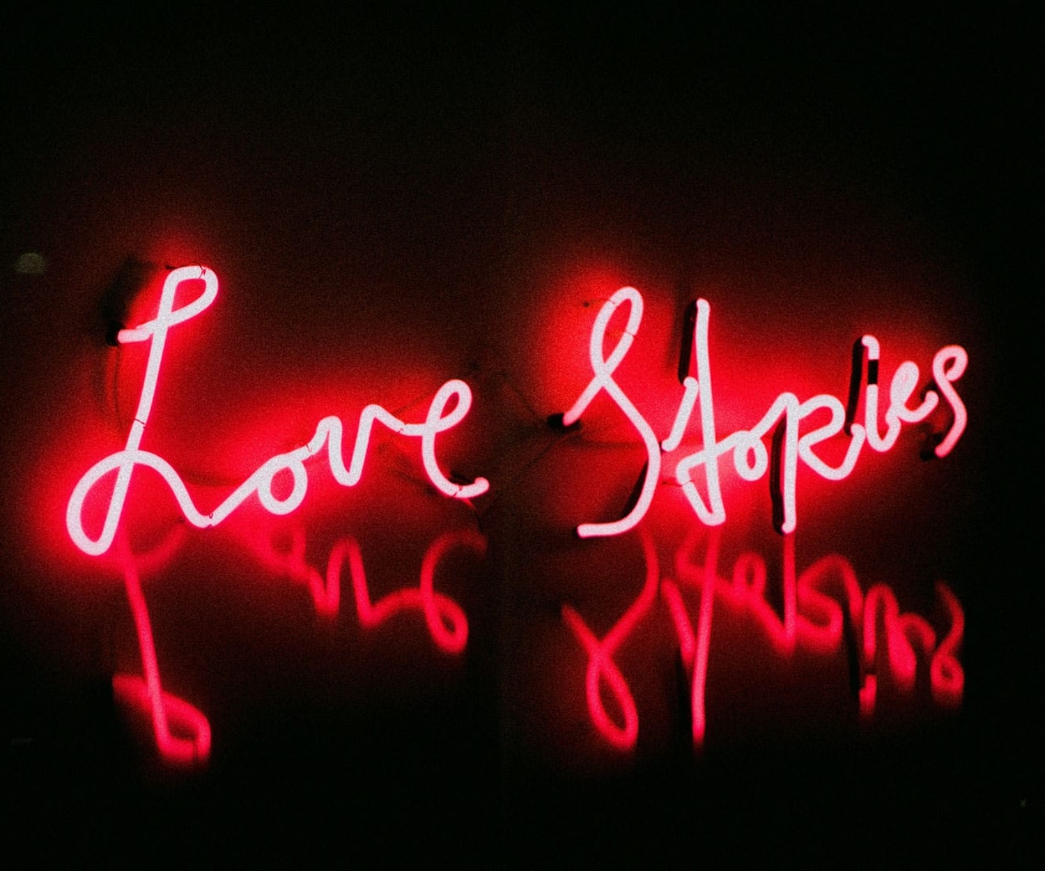 Rote Neon-Leuchtschrift mit dem Schriftzug „Love Stories“ als Symbol für emotionales Storytelling.