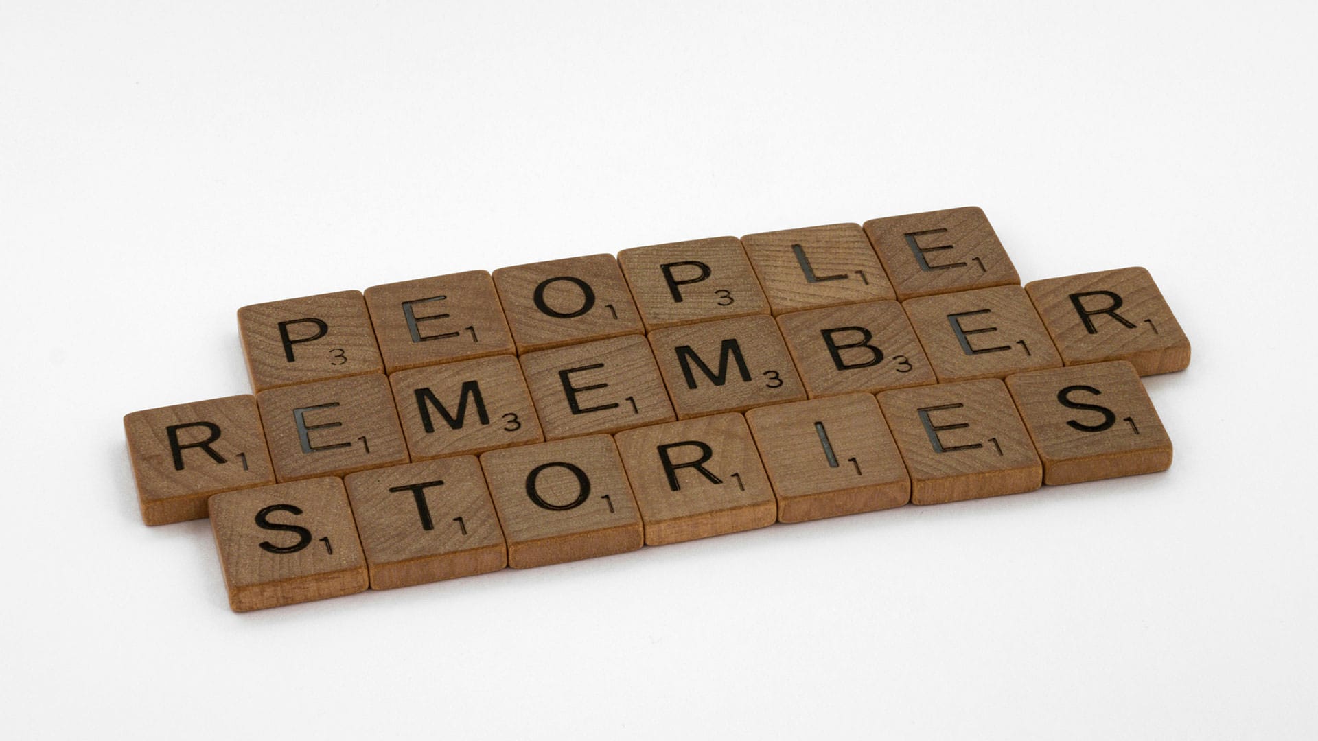 Scrabble-Holzsteine bilden den Satz „People remember stories“, passend für Video-Storytelling.