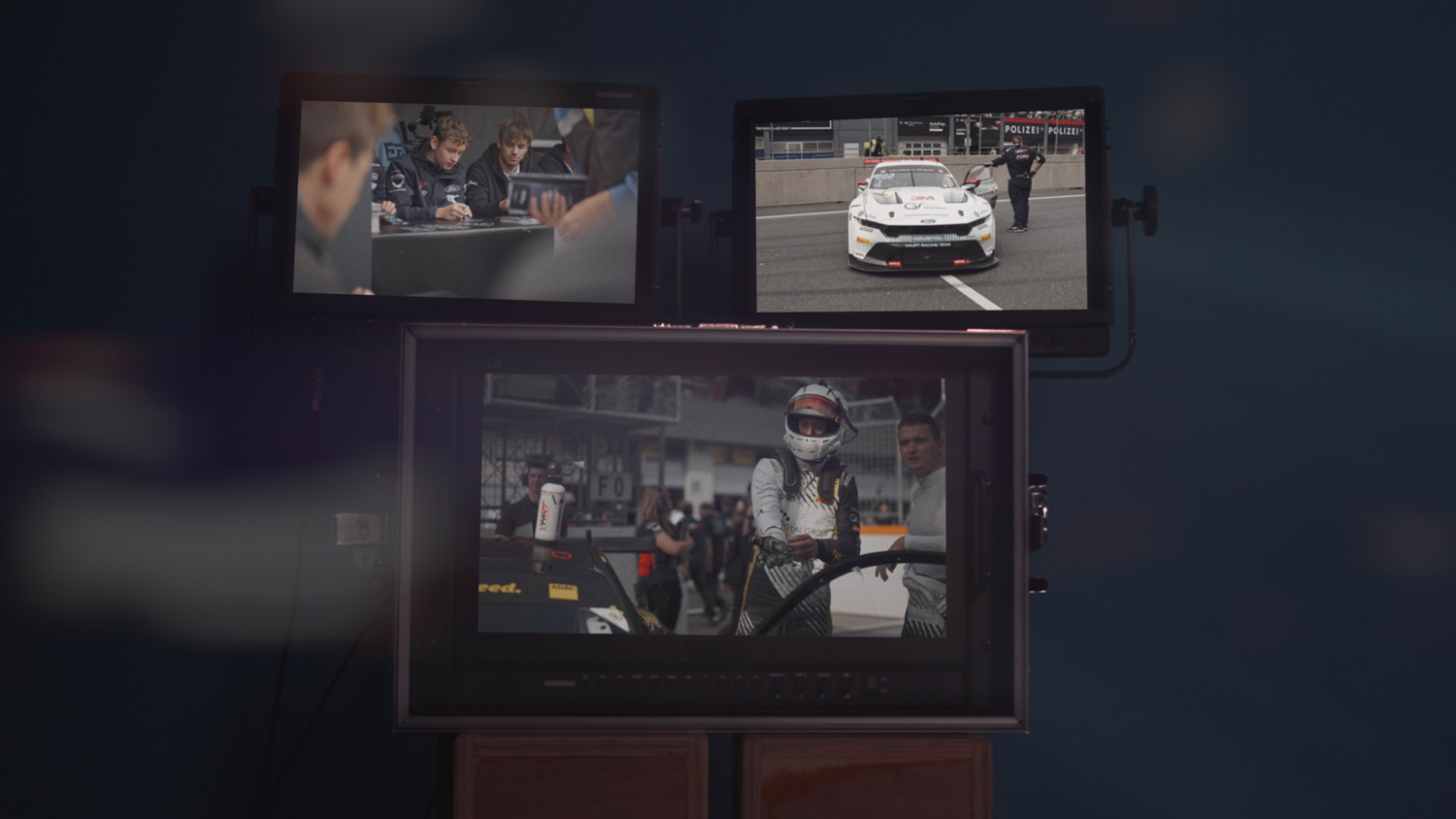 Drei Monitore zeigen Szenen aus den ADAC GT Masters und ADAC GT4 Germany Jahresfilmen 2025 – Motorsportfilmproduktion im Studio