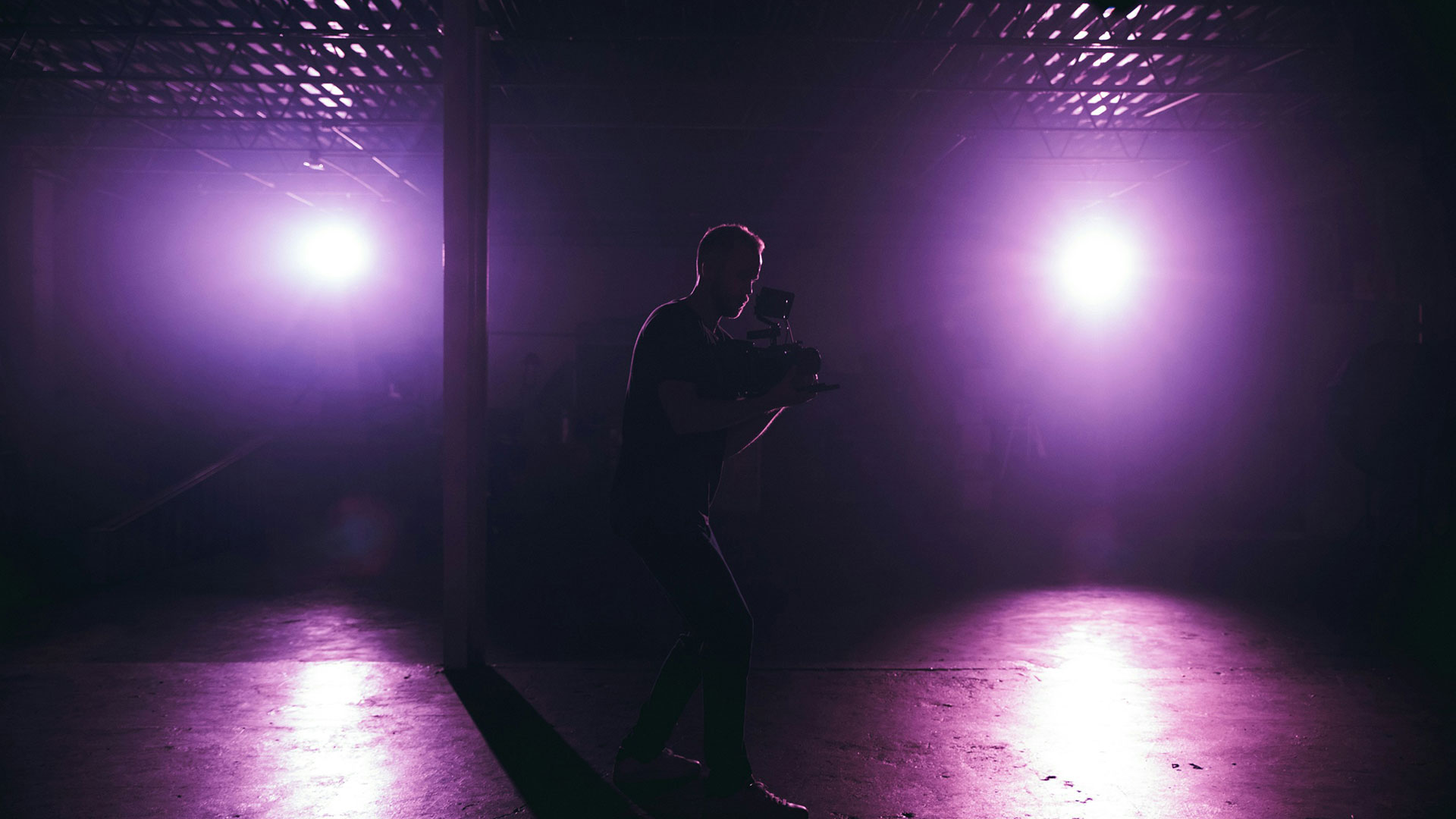 Kameramann bei der Arbeit im Studio mit Lichteffekten, stellvertretend für den Produktionsaufwand und die Kosten eines Unternehmensfilms