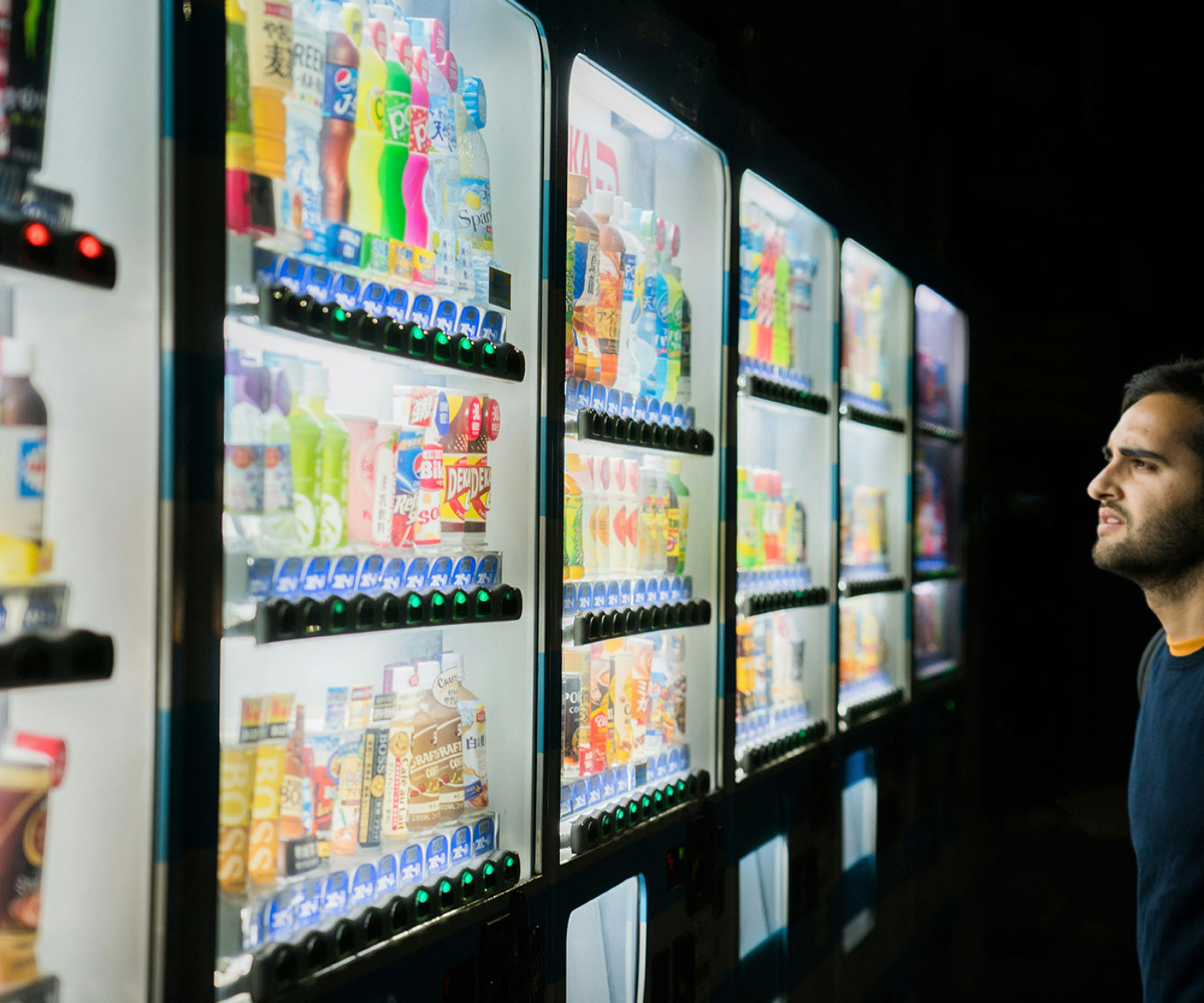 Ein Mann steht vor einer Auswahl an beleuchteten Automaten und symbolisiert die Entscheidung zwischen unterschiedlichen Videoarten für Marketingziele.
