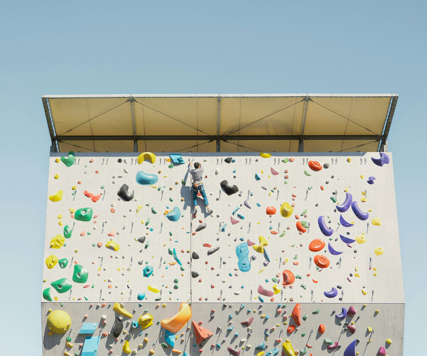 Symbolbild für den Aufstieg durch Videos im Content Marketing, mit einer Person an einer bunten Kletterwand
