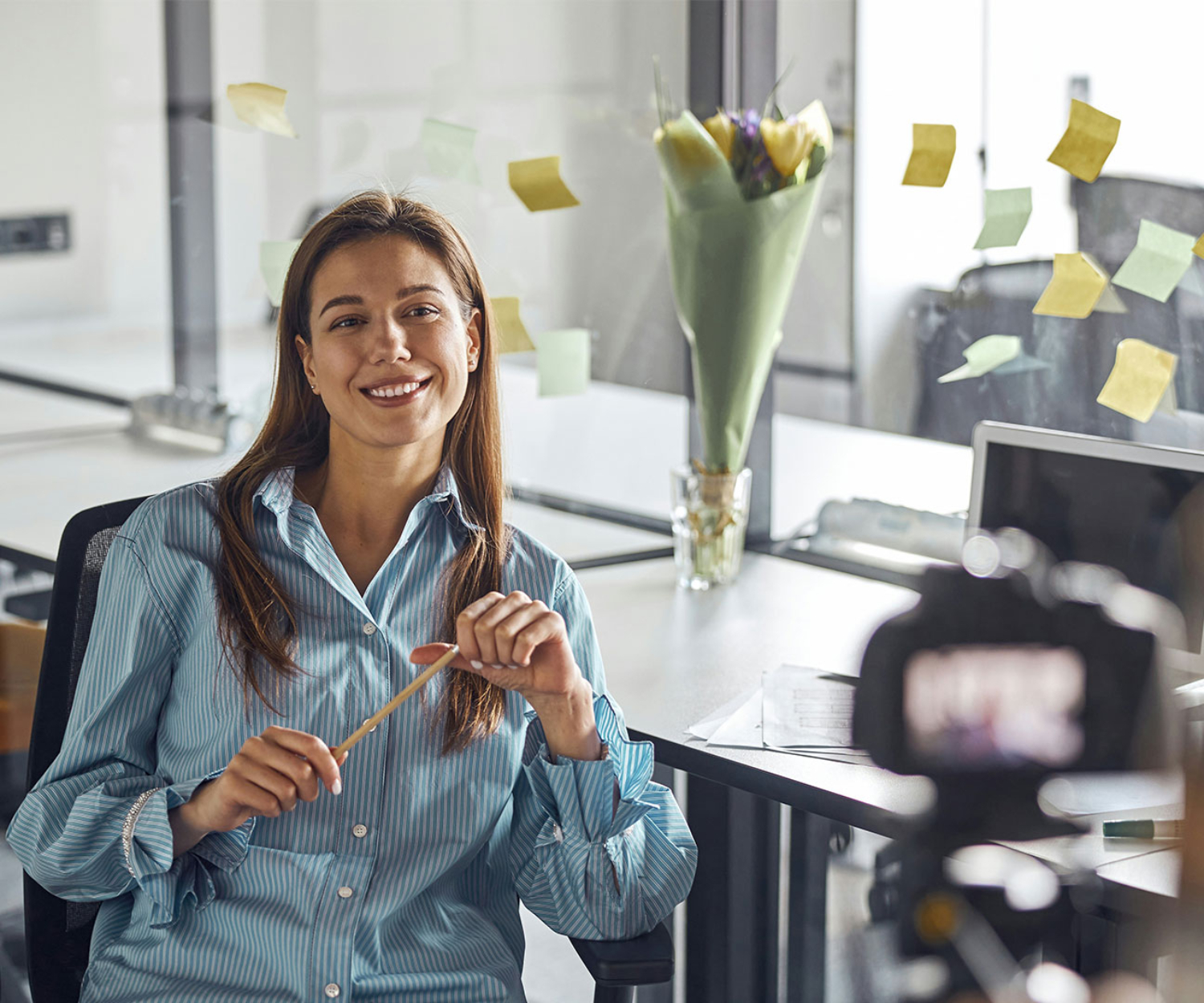 Mitarbeiterin spricht vor der Kamera für einen Unternehmensvlog im Büro